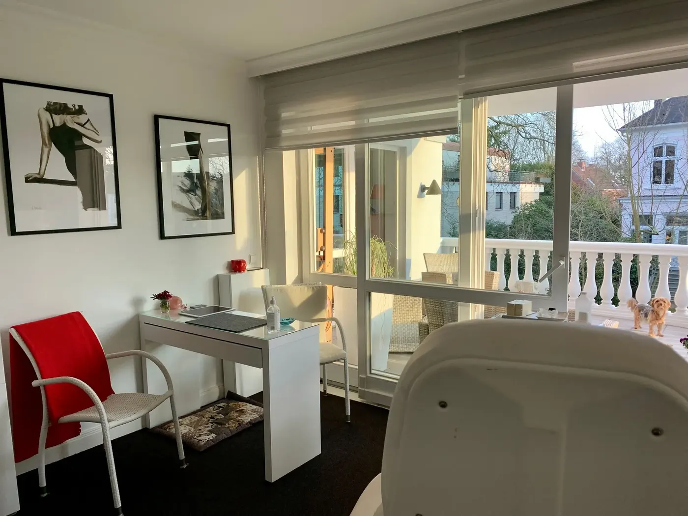 Behandlungsraum mit großer Fensterfront und Blick auf die Häuser der Nachbarschaft